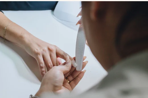 A customer having a gel manicure at a salon station.